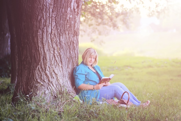 mulher no parque ao pôr do sol com livro