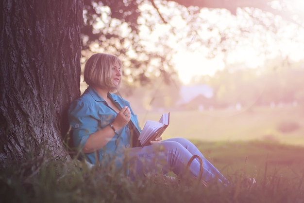 Foto mulher no parque ao pôr do sol com livro