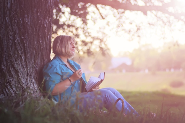 Mulher no parque ao pôr do sol com livro