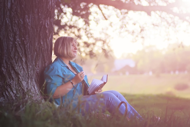 mulher no parque ao pôr do sol com livro