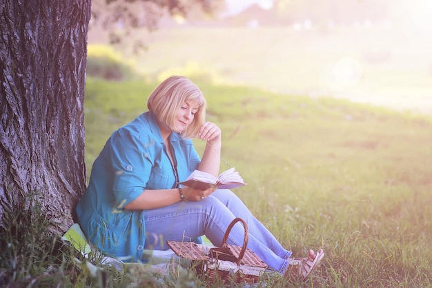 mulher no parque ao pôr do sol com livro