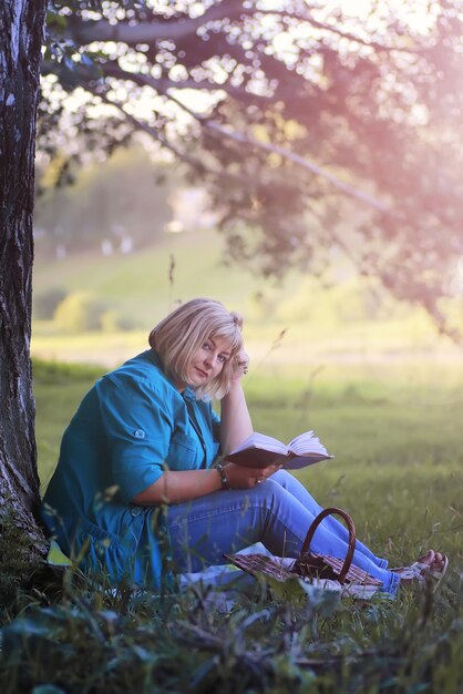 mulher no parque ao pôr do sol com livro