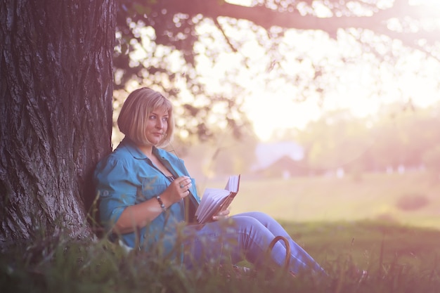 Mulher no parque ao pôr do sol com o livro