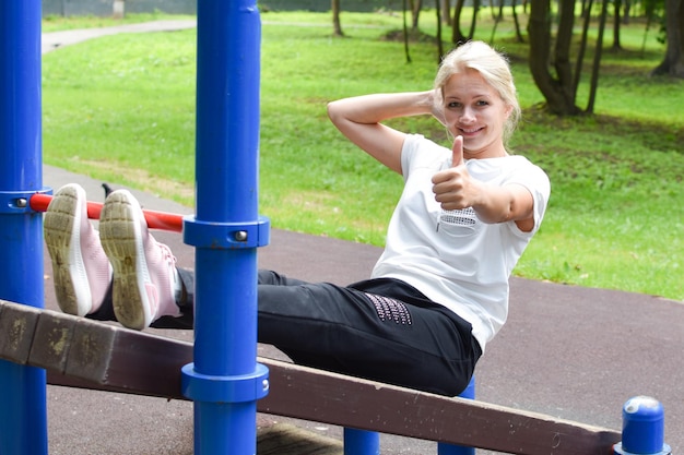 mulher no parque está envolvida em ginástica menina na barra horizontal ginástica do lado de fora