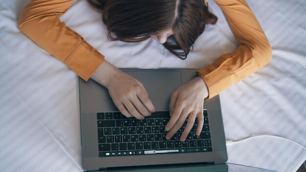 Mulher no quarto deitado na cama laptop trabalho estilo de vida tecnologia