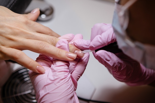 Mulher no salão de beleza recebendo manicure por esteticista de unhas