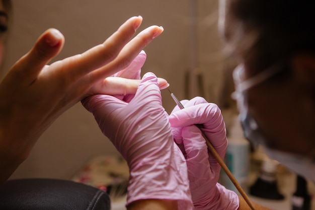 Mulher no salão de beleza recebendo manicure por esteticista de unhas