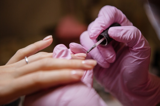 Mulher no salão de beleza recebendo manicure por esteticista de unhas