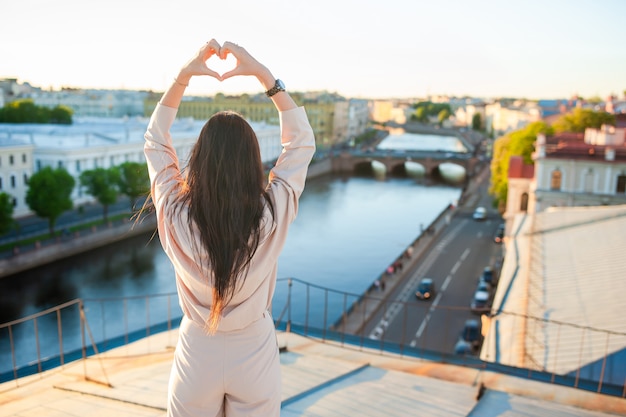 Mulher no telhado desfrutando com vista do belo pôr do sol em São Petersburgo na Rússia