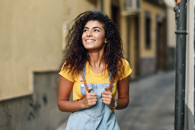 Mulher norte-africana nova com penteado curly preto ao ar livre.