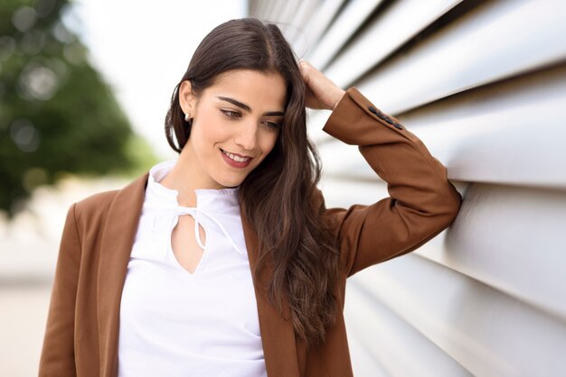 Mulher nova com o cabelo longo ondulado agradável que desgasta o vestuário formal.