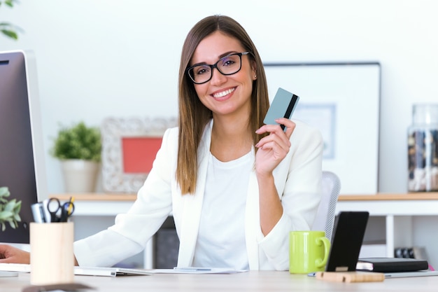 Mulher nova de negócios usando cartão de crédito na loja online.