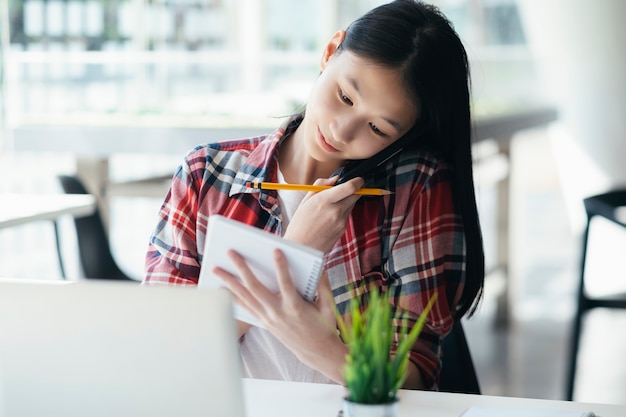 Mulher nova do escritório que fala no telefone móvel com o cliente.