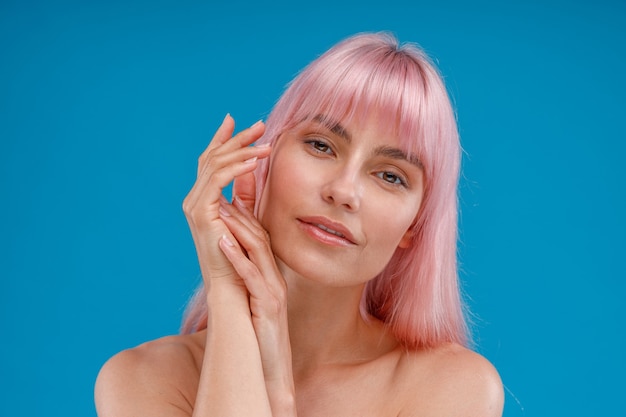 Mulher nua sensual com cabelo rosa e pele brilhante perfeita olhando para a câmera posando isolada