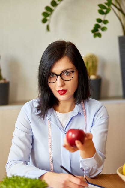 Mulher nutricionista no escritório, segurando maçã na mão