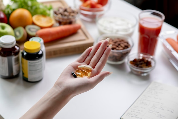 Mulher nutricionista profissional verificando suplementos dietéticos na mão, cercada por uma variedade de frutas, nozes, vegetais e suplementos dietéticos na mesa