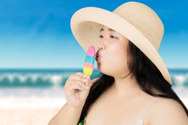 Mulher obesa beijando sorvete na praia