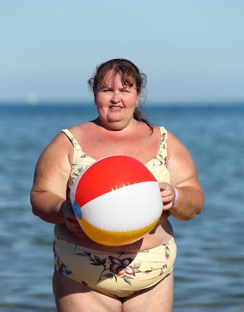 Mulher obesa com bola na praia