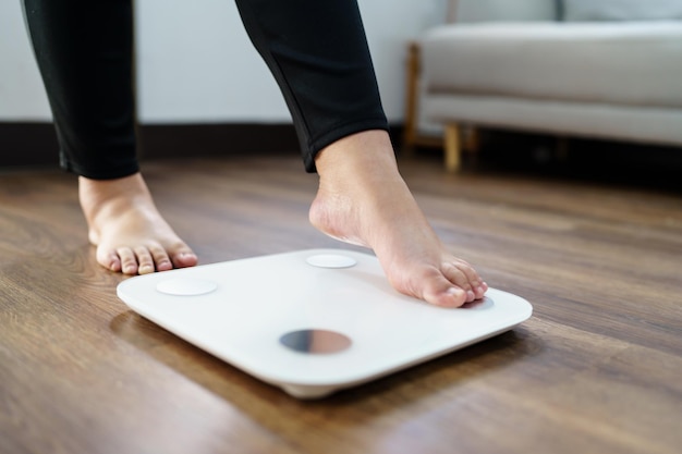 Mulher obesa com gordura chateada entediada de fazer dieta Falha na perda de peso Dieta gorda e balança mulher asiática triste na escala de peso no controle de peso em casa