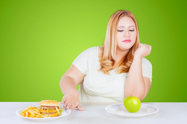 Mulher obesa recusando junk food na mesa