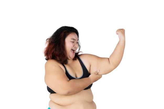 Mulher obesa triste mostra seu bíceps flácido no estúdio