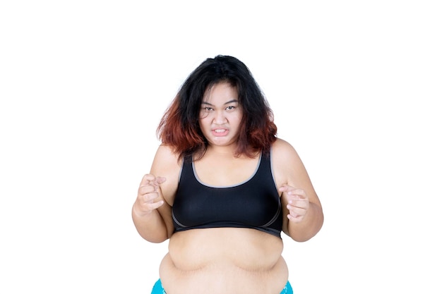 Mulher obesa zangada a usar roupa desportiva no estúdio.