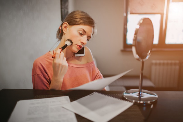 Mulher ocupada fazendo uma maquiagem, falando ao telefone, lendo documentos ao mesmo tempo. empresária, fazendo várias tarefas. pessoa de negócios multitarefa.