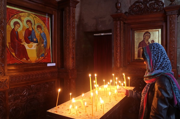 Mulher oferecendo uma vela na histórica igreja do mosteiro de jvari mtskheta town, geórgia