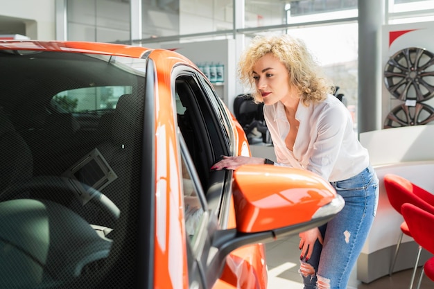 Mulher olha carro na concessionária