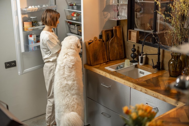 Mulher olha para uma geladeira com seu cachorro