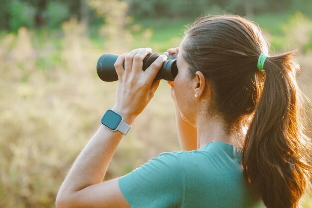 Mulher olhando através de binóculos para a natureza do Pantanal, no Brasil