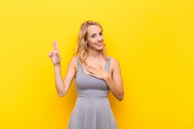 Mulher olhando feliz, confiante e confiável, sorrindo e mostrando sinal de vitória, com uma atitude positiva