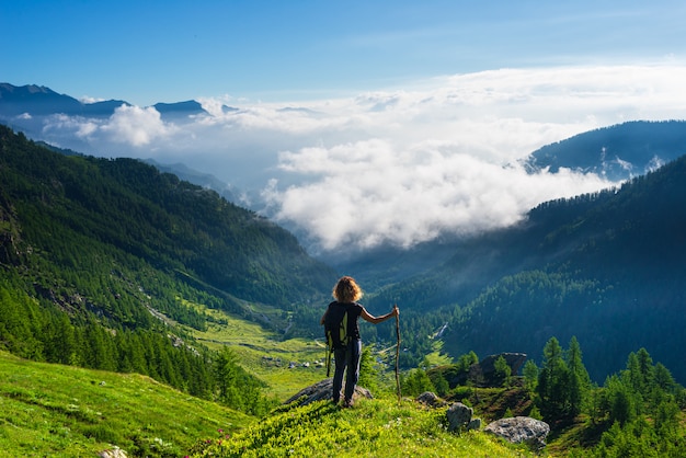 Mulher olhando nuvens de paisagem dramática sobre o vale, céu azul claro