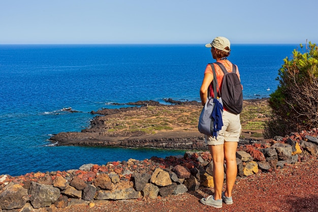 Mulher olhando o mar do topo do vulcão chamado Monte Nero Linosa Sicília