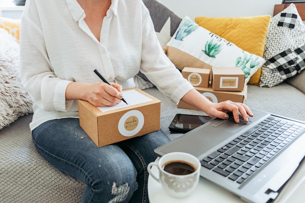 Foto mulher olhando os clientes cadastrados em seu laptop e escrevendo o nome em uma caixa