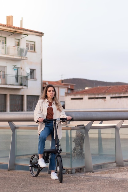 Mulher olhando para a câmera enquanto andava de bicicleta elétrica indo para casa em uma cidade europeia pobre com espaço de cópia