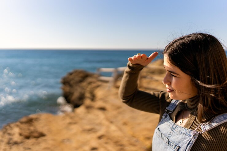 Foto mulher olhando para a distância à beira-mar no verão