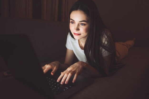 Mulher olhando para a tela de um laptop, digitando um texto