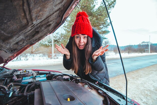 mulher olhando para assistência rodoviária com motor de carro