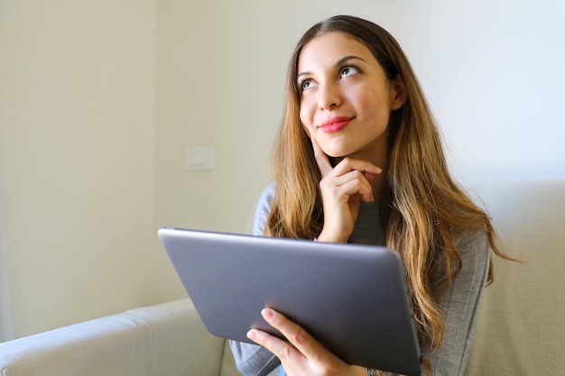 Foto mulher olhando para cima e pensando ou desejando segurando a tela de toque do computador tablet