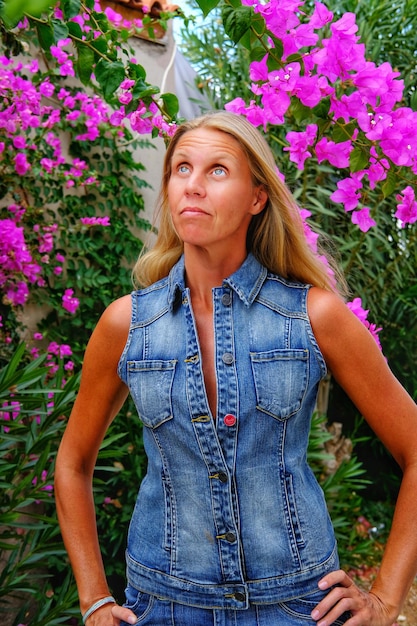 Foto mulher olhando para cima enquanto está de pé com as mãos no quadril contra a planta em flor