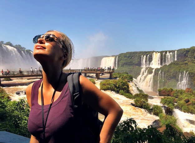 Foto mulher olhando para longe com óculos de sol contra o céu