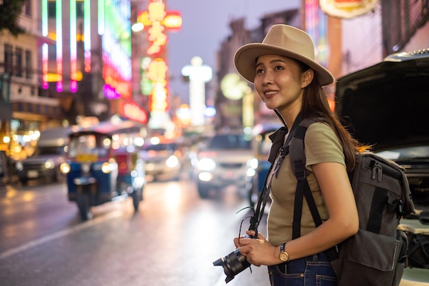 Foto mulher olhando para longe enquanto está de pé na rua iluminada na cidade à noite