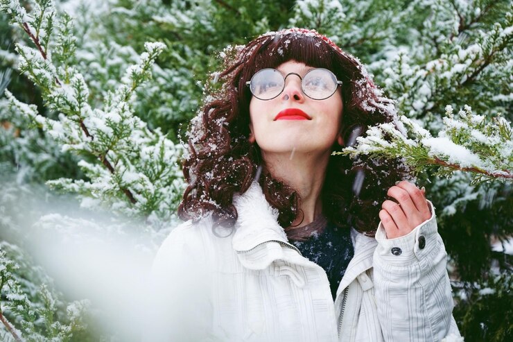 Foto mulher olhando para longe enquanto toca árvore durante o inverno