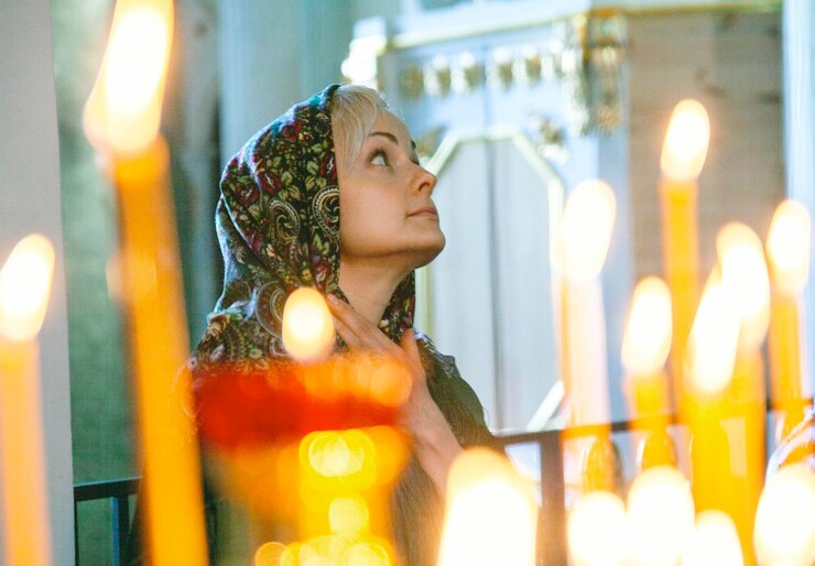 Foto mulher olhando para longe na igreja com velas iluminadas