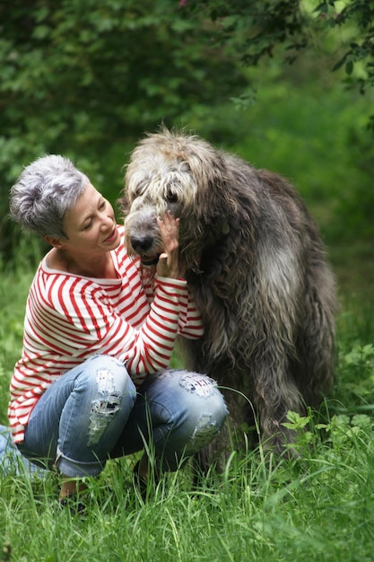 Foto mulher olhando para o cão enquanto se agacha no campo