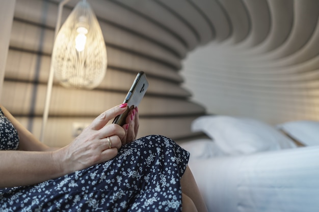 Mulher olhando para o celular enquanto descansava no quarto à noite