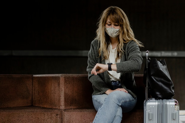 Mulher olhando para o relógio enquanto espera o trem durante a pandemia do coronavírus