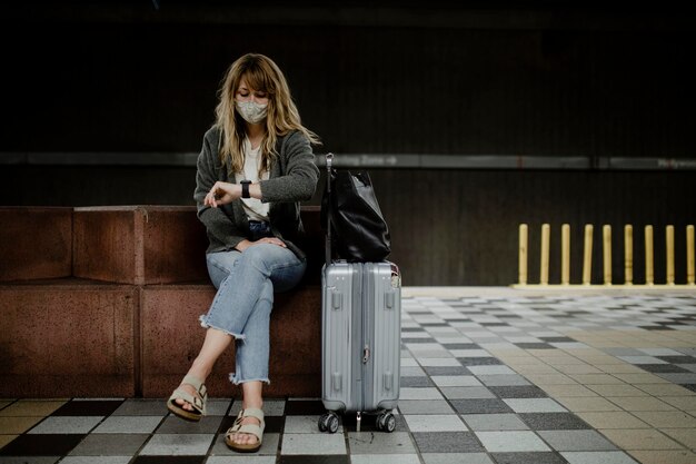 Foto mulher olhando para o relógio enquanto espera o trem durante a pandemia do coronavírus