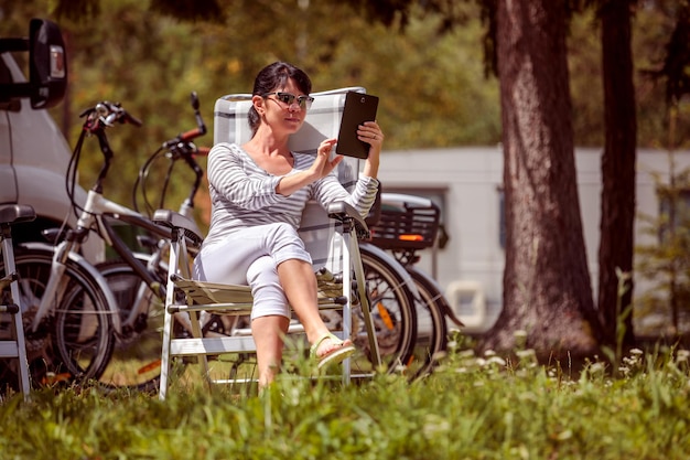 Mulher olhando para o tablet perto do camping. Férias de carro de caravana. Viagem de férias em família, viagem de férias em motorhome RV. Tecnologia de comunicação de informações de conexão Wi-fi.